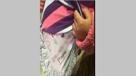 Fotografía difundida por la Patrulla Fronteriza en la cual se observa el teléfono anotado bajo el suéter de una niña de cuatro años que cruzó sola hacia Estados Unidos.