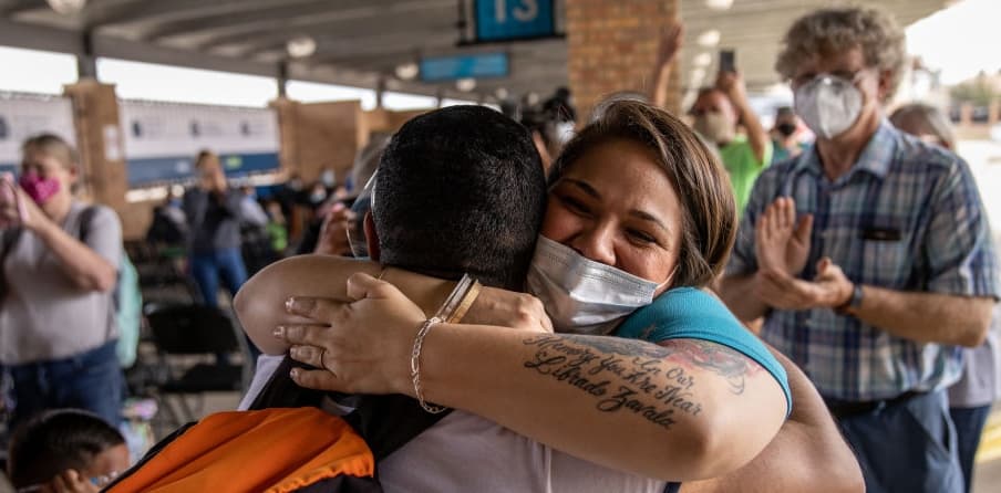 A volunteer welcomes a group of at least 25 immigrant asylum seekers who were officially allowed to cross from a migrant camp in Mexico into the United States on February 25, 2021 in Brownsville, Texas.