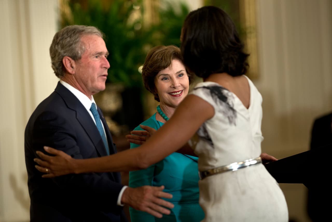 Los Bush fueron constantes invitados a la Casa Blanca mientras los Obama vivieron en ella. En esta foto del 3 de mayo de 2012, se ve a Michelle Obama dándole la bienvenida a sus invitados. La cercanía con los demócratas causó un poco de incertidumbre y confusión durante las elecciones porque parecía que la pareja no parecía mostrar su apoyo por el candidato de su partido, Donald Trump.