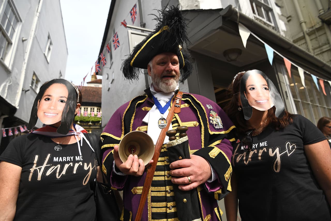 Algunas chicas tal vez guardan la esperanza de conquistar al
<b>"<a href="https://www.univision.com/entretenimiento/adios-al-principe-rebelde-como-harry-encontro-su-camino-al-altar-y-se-reconcilio-con-su-destino">soltero más codiciado</a>" </b>y se han paseado por el lugar con camisetas que leen 'Harry, cásate conmigo', aunque sus rostros están cubiertos con máscaras de Meghan Markle.