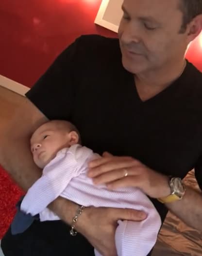 El pequeño luce muy relajado después de comer, mientras su papi lo arrulla.