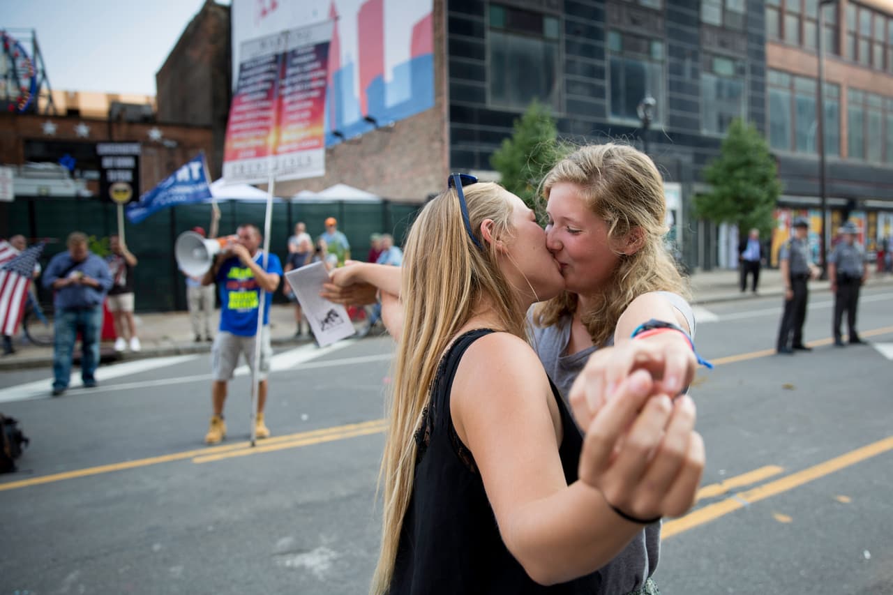 MARTES 19 DE JULIO. 6:51 PM. Una pareja gay posa para los fotógrafos frente a un predicador religioso que protesta contra el movimiento LGTB frente al auditorio de la convención republicana.