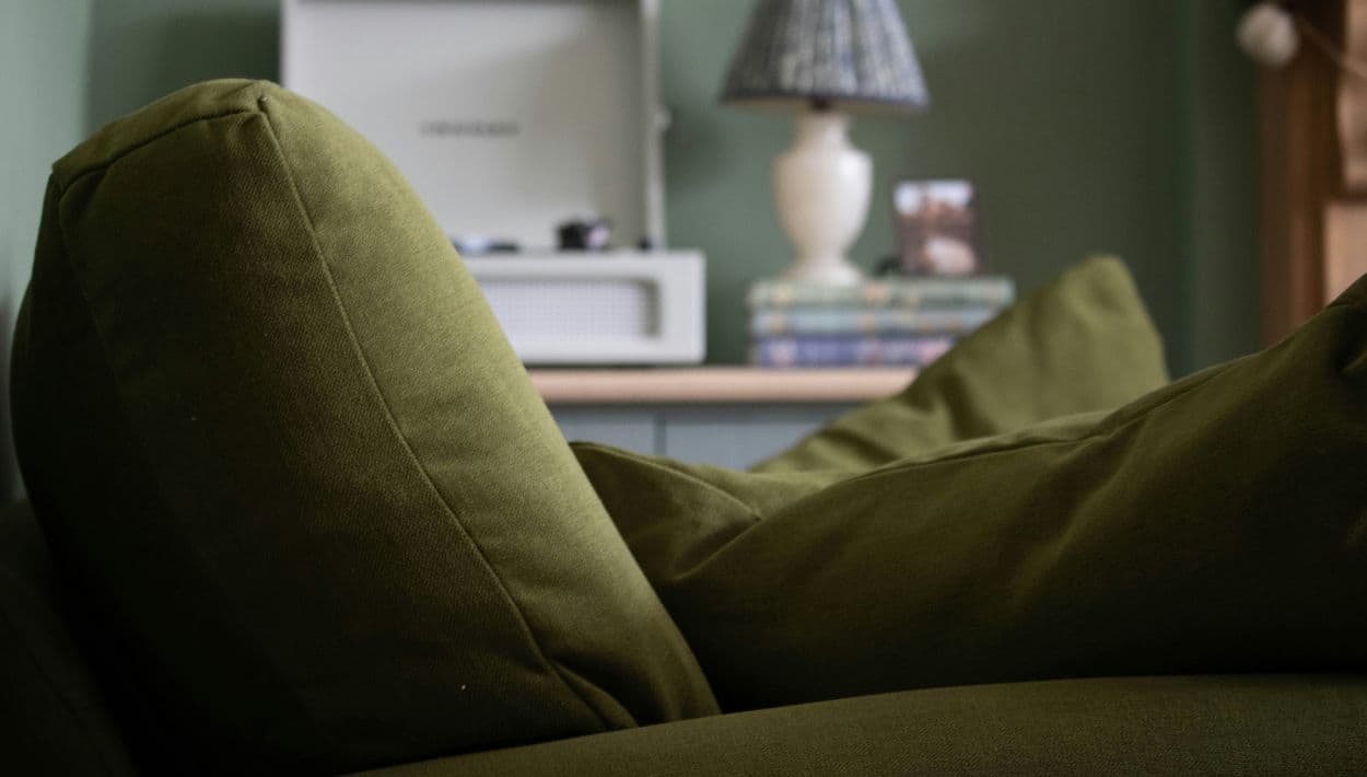 Un sillón verde olivo destaca como pieza central en un hogar de estilo cálido y contemporáneo.