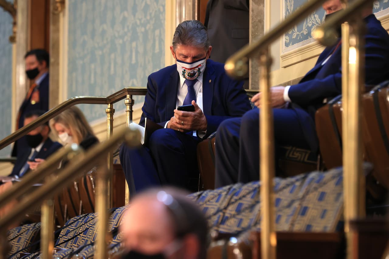 El senador demócrata Joe Manchin revisa su teléfono poco antes de que iniciara el discurso de Biden. El presidente habló sobre las acciones que planea alcanzar con su gobierno en salud, economía y en la escena internacional.