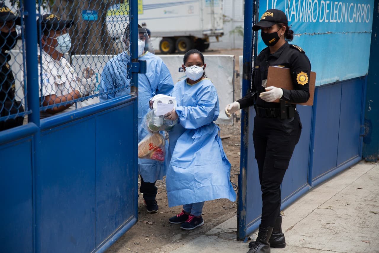 Estos trabajadores de la salud traen a las personas retenidas en otro refugio temporal en Ciudad de Guatemala algunos suministros y provisiones entregados fuera por sus familiares.