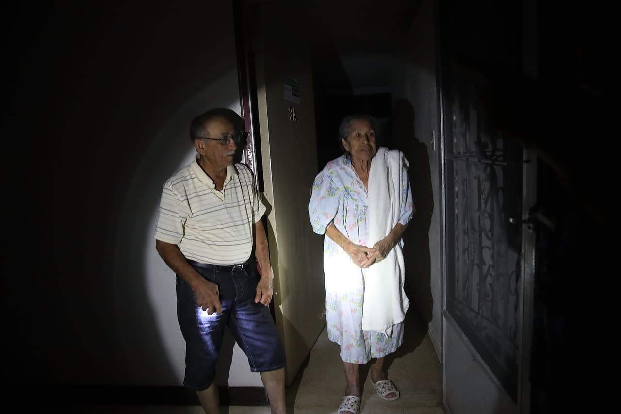 SAN JUAN, PUERTO RICO - SEPTEMBER 30: Enrique Rodriguez and Angela Medina talk with their neighbors at the doorway to their dark apartment as they and other residents of the 62 and over Moradas Las Teresas's Uno and Dos condo units deal with no electricty in the aftermath of Hurricane Maria on September 30, 2017 in San Juan, Puerto Rico. Many of the elderly are having to deal with conditions such as no electricity so they can't take the elevator down from high floors nor can they get water except for a couple hours a day. Taking medication and other basic life sustaining functions have become very difficult for many of the residents. (Photo by Joe Raedle/Getty Images)