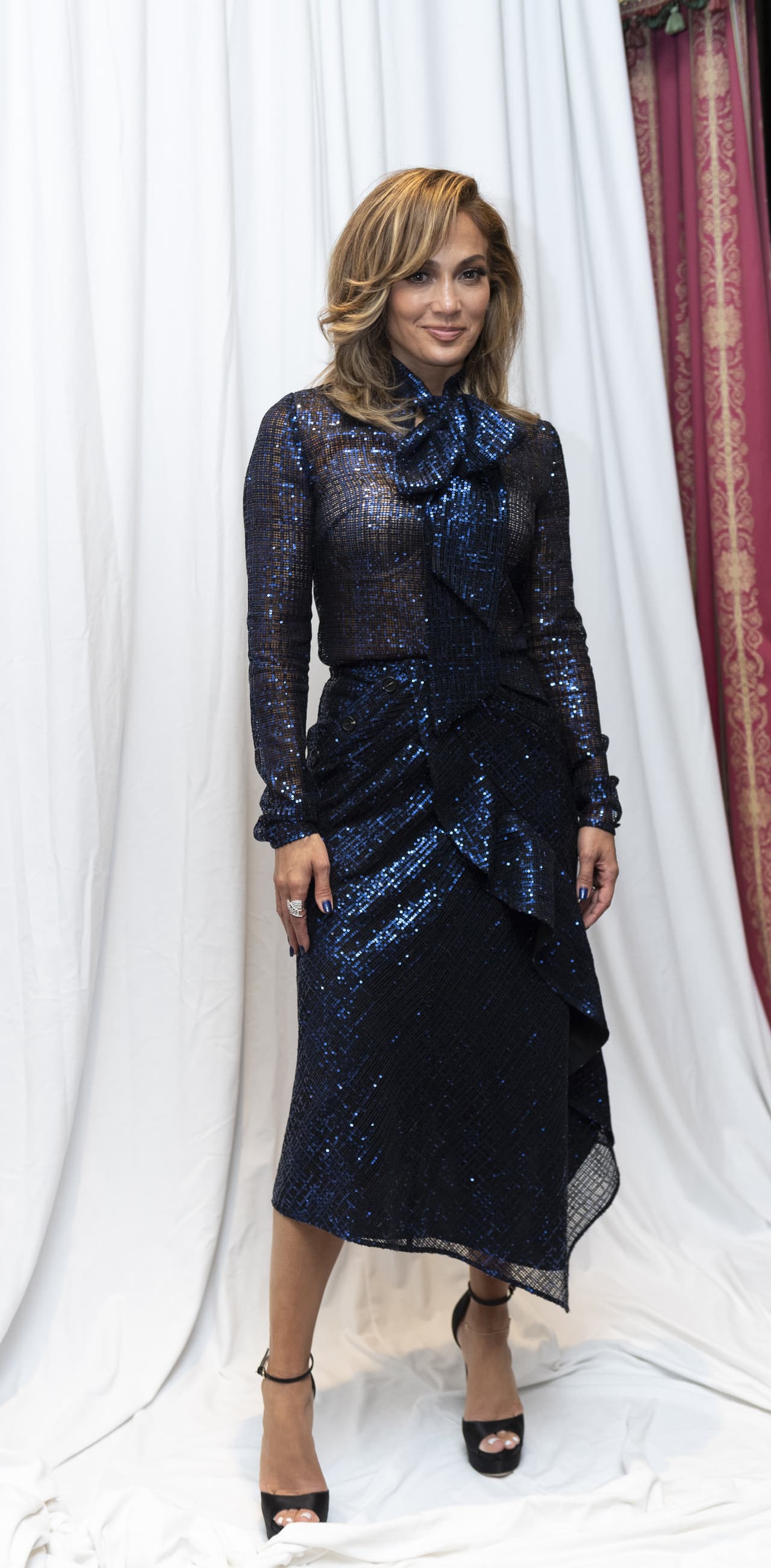 <b>Look 3</b>
<br>En la conferencia de prensa de la cinta durante su estancia en Toronto, J.Lo usó una camisa de manga larga de lentejuelas y lazo al cuello de 
<b><a href="https://www.self-portrait-studio.com/check-sequin-pussy-bow-blouse" target="_blank">Self-Portrait</a> </b>($320) en azul con 
<b><a href="https://www.self-portrait-studio.com/new-arrivals/check-sequin-midi-skirt" target="_blank">falda asimétrica</a></b> midi en conjunto ($308).