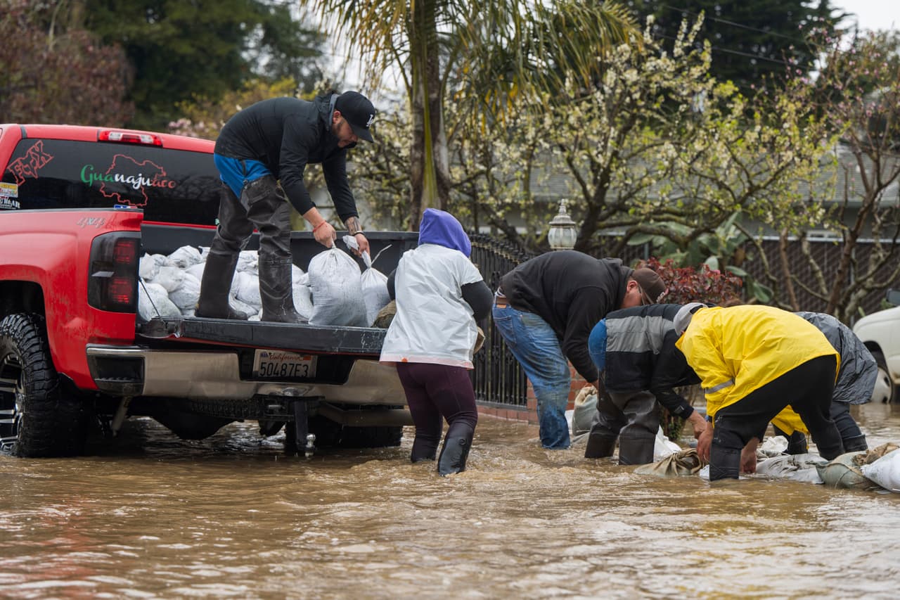 La gente coloca sacos de arena en College Road en Watsonville. Oficiales de distintas corporaciones, apoyados por la Guarda Nacional de California, comenzaron desde el viernes por la noche a tocar de puerta en puerta para instar a los residentes a salir 
<a href="https://www.univision.com/local/san-francisco-kdtv/como-se-forman-los-rios-atmosfericos-y-por-que-son-peligrosos-para-california">antes de que llegaran las lluvias</a>, pero algunos se quedaron y tuvieron que ser sacados de las aguas a primera hora del sábado.