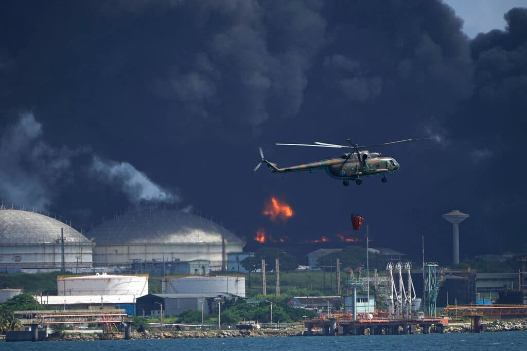 Un helicóptero con agua sobrevuela la Base de Supertanques de Matanzas, mientras los bomberos intentan sofocar el incendio que comenzó durante una tormenta eléctrica la noche anterior, en Matazanas, Cuba, el sábado 6 de agosto de 2022.
