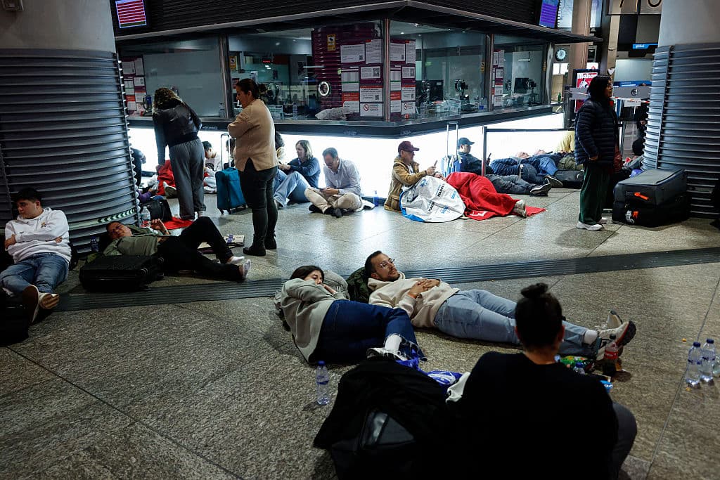 Personas duermen y esperan en la estación de Atocha de Madrid, hasta que se restablezca el servicio de trenes.