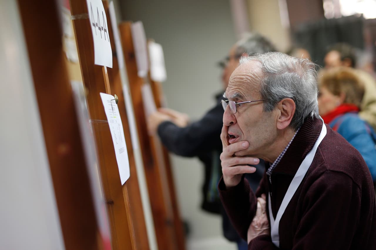 Este elector se busca en las listas de votantes que pegaron en las paredes de un centro electoral en Barcelona.