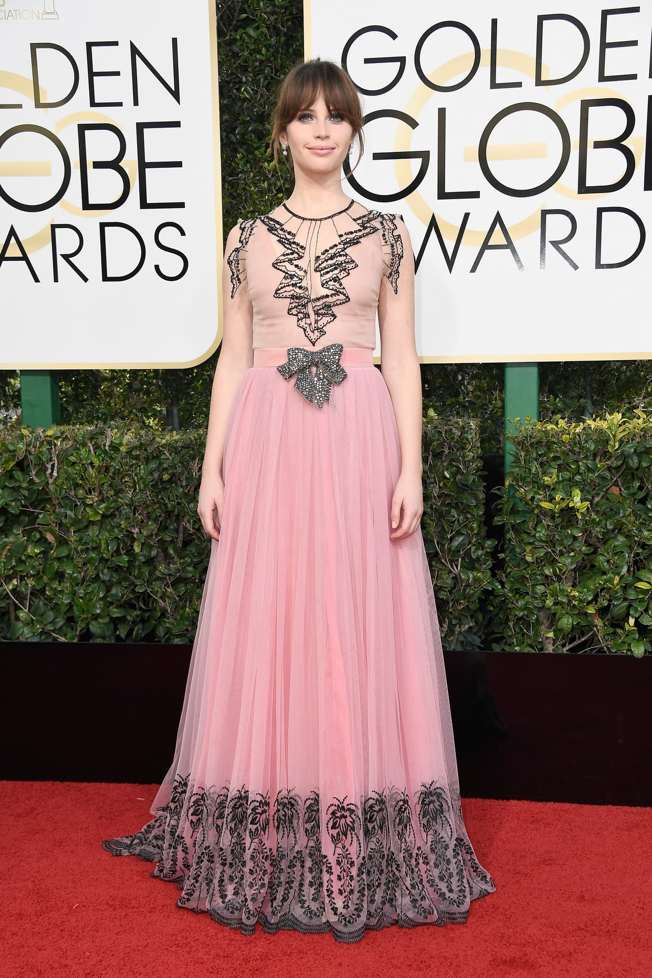 Felicity Jones con un vestdo rosa de Gucci con trampantojos bordados en negro.