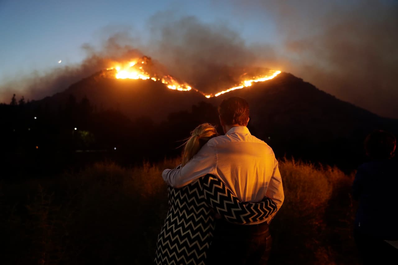 Roger Bloxberg, a la derecha, y su esposa Anne se abrazan mientras observan un incendio forestal en la cima de una colina cerca de su casa en West Hills. AP/Marcio Jose Sanchez