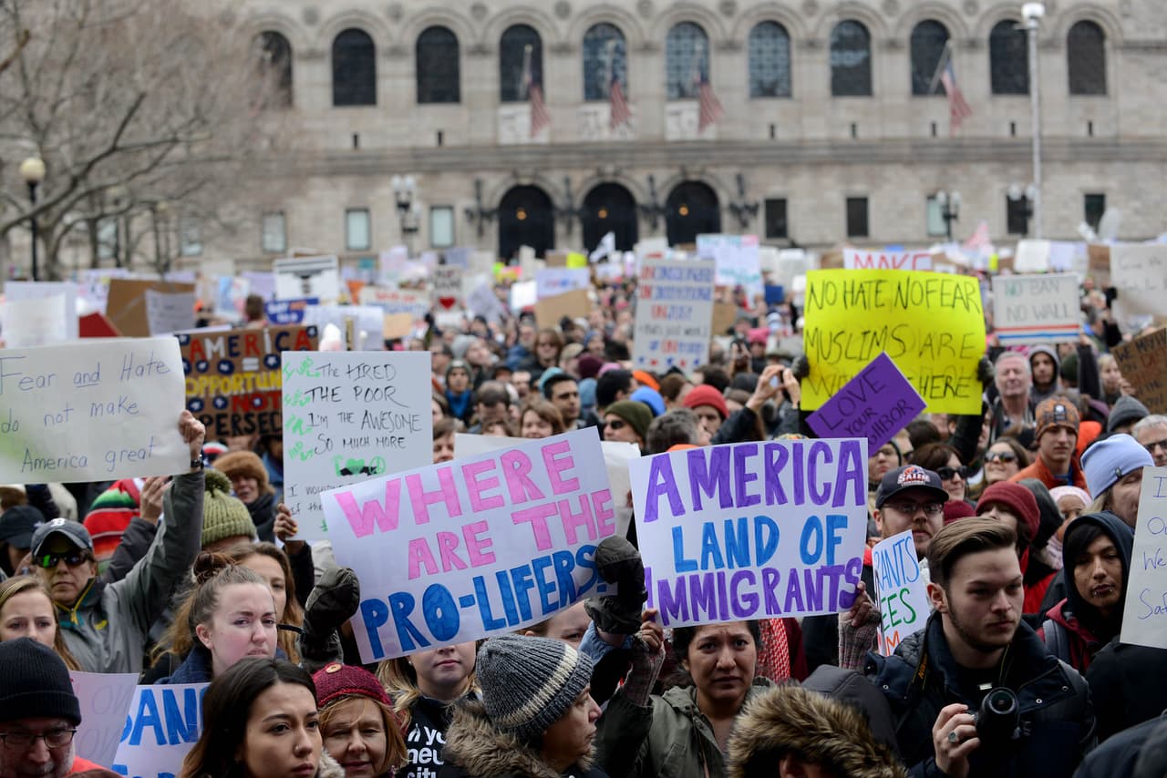 Carteles de: "América es la tierra de los inmigrantes" y "¿Dónde están los pro vida?" delante de la Biblioteca Pública de Boston.