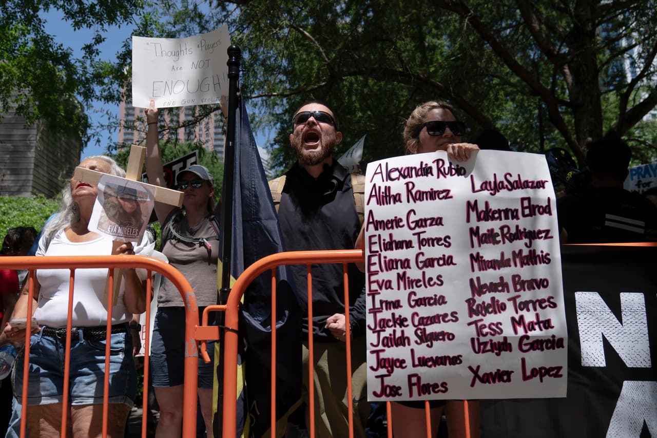 Un manifestante sostiene un cartel con los nombres de las víctimas del tiroteo en una escuela primaria de Uvalde. La convención de la NRA es la primera que organiza la asociación desde 2019, luego de una pausa de dos años debido a la pandemia. La NRA ha estado tratando de ganar fuerzas luego de un período de serias turbulencias legales y financieras que incluyeron 
<a href="https://www.univision.com/noticias/politica/nueva-york-nra-bancarrota-rechazo-demanda" target="_blank">una solicitud (fallida) de bancarrota</a>, una demanda colectiva y una investigación de fraude por parte del fiscal general de Nueva York.