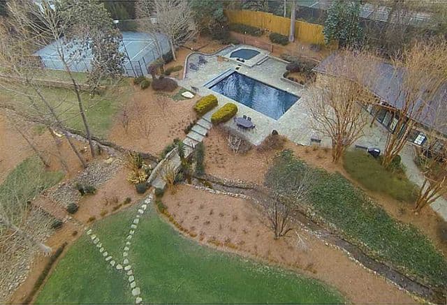 Tiene paredes de roca, jardines, piscina y un campo de tenis.