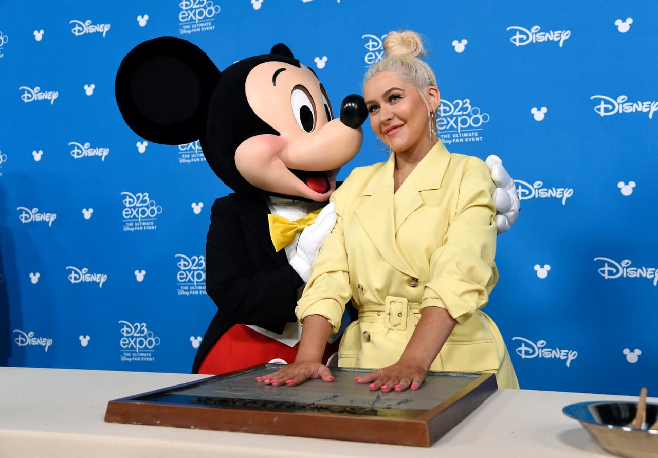Christina Aguilera recibiendo un 'apapacho' de Mickey Mouse.
