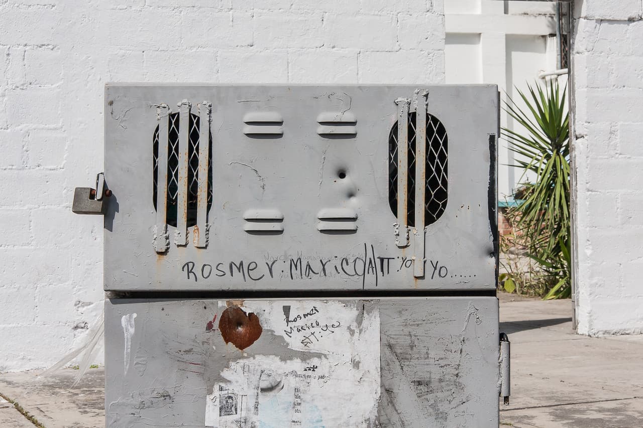 En el municipio Ambrosio Plaza, donde está ubicada la escuela, se reportan 83 homicidios por cada 100,000 habitantes, según el último balance de la criminalidad elaborado por el Instituto Autónomo de Policía del estado Miranda. Si el municipio fuera un país, sería el segundo más violento del mundo si se compara con las cifras de la ONU. La imagen muestra la huella de un disparo sobre una cabina de cableado telefónico que está justo a la entrada del colegio.