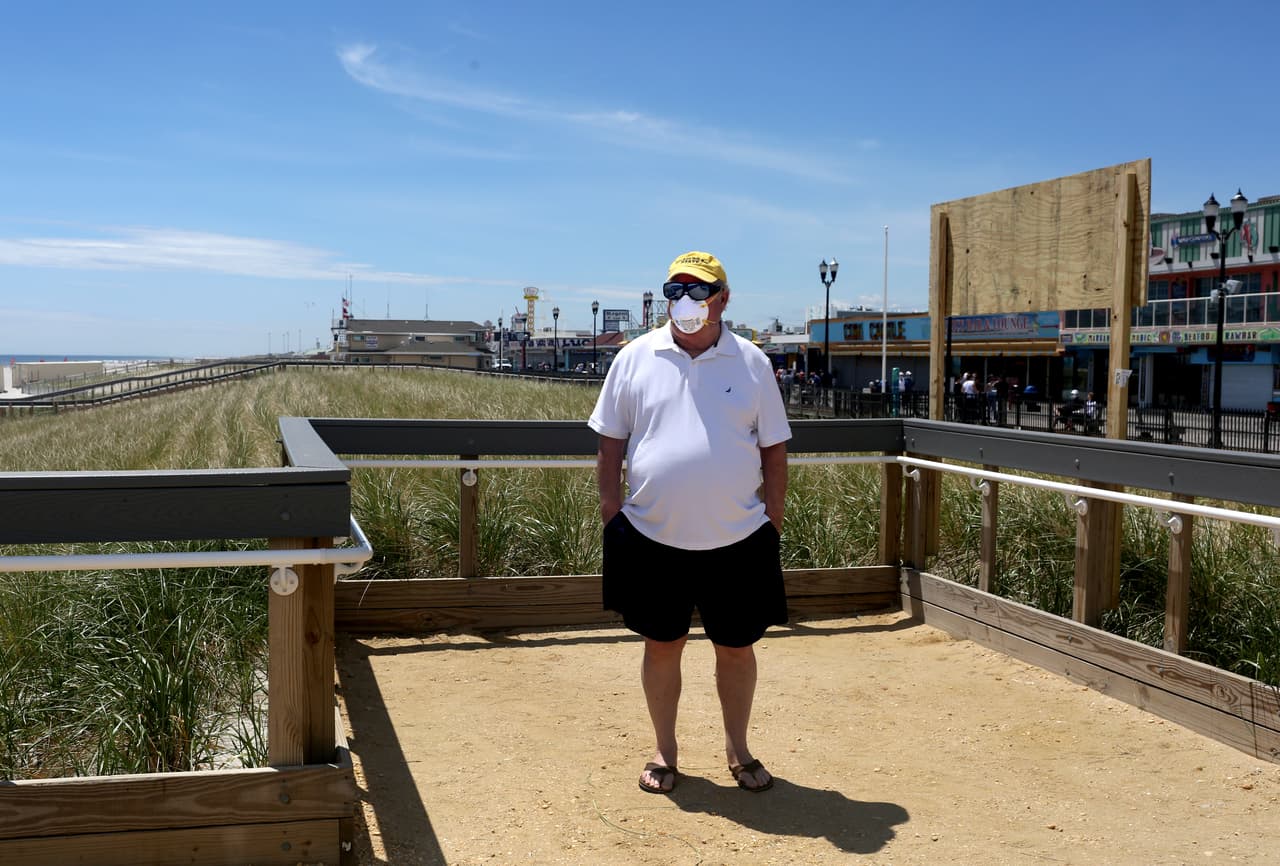 Un hombre con mascarilla espera antes de entrar a la playa.