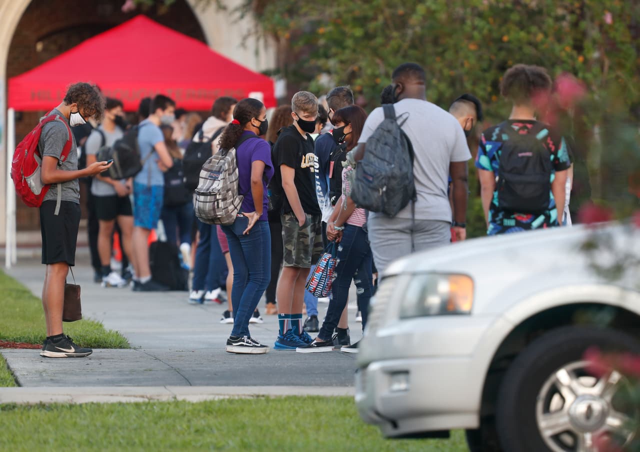 Los estudiantes deben esperar a que se les tome la temperatura a la entrada de las escuelas y llevar mascarillas.