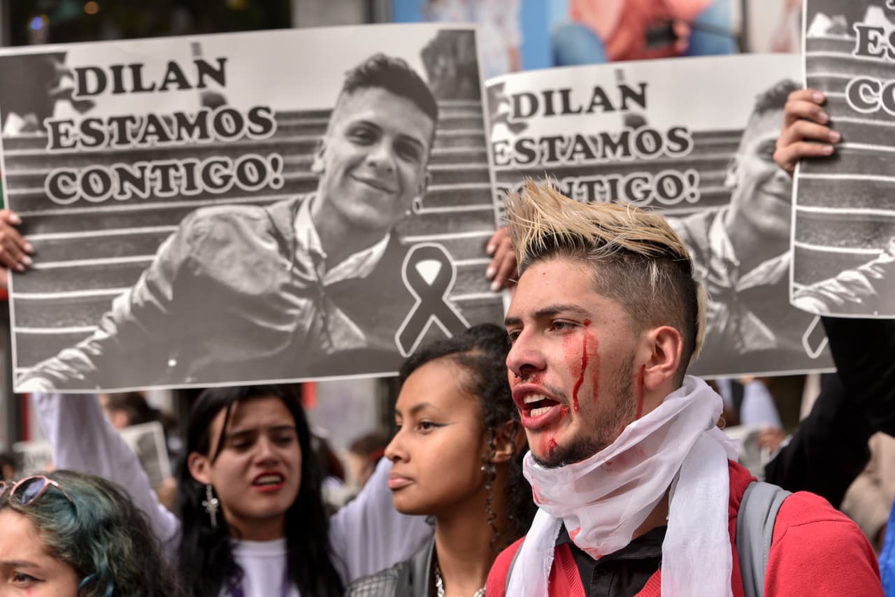 <b>"Dilan estamos contigo",</b> se lee en otra de las pancartas levantadas por jóvenes manifestantes en una protesta el 26 de noviembre del 2019 en Bogotá. El joven falleció luego de que en su cabeza impactó una 
<b>"una bolsa de material textil que contiene múltiples perdigones de plomo"</b>, de acuerdo con declaraciones de Claudia García, directora de Medicina Legal en la capital colombiana.