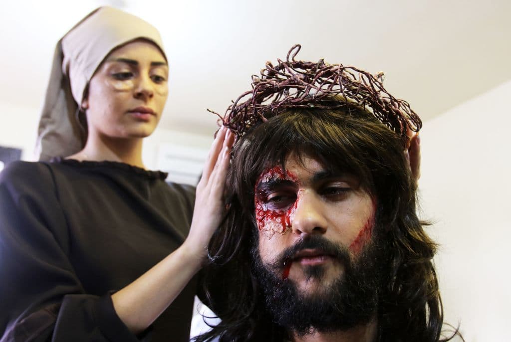 En Líbano, una mujer da toques finales al maquillaje del actor que representará a Jesucristo, colocándole su "corona de espinas".