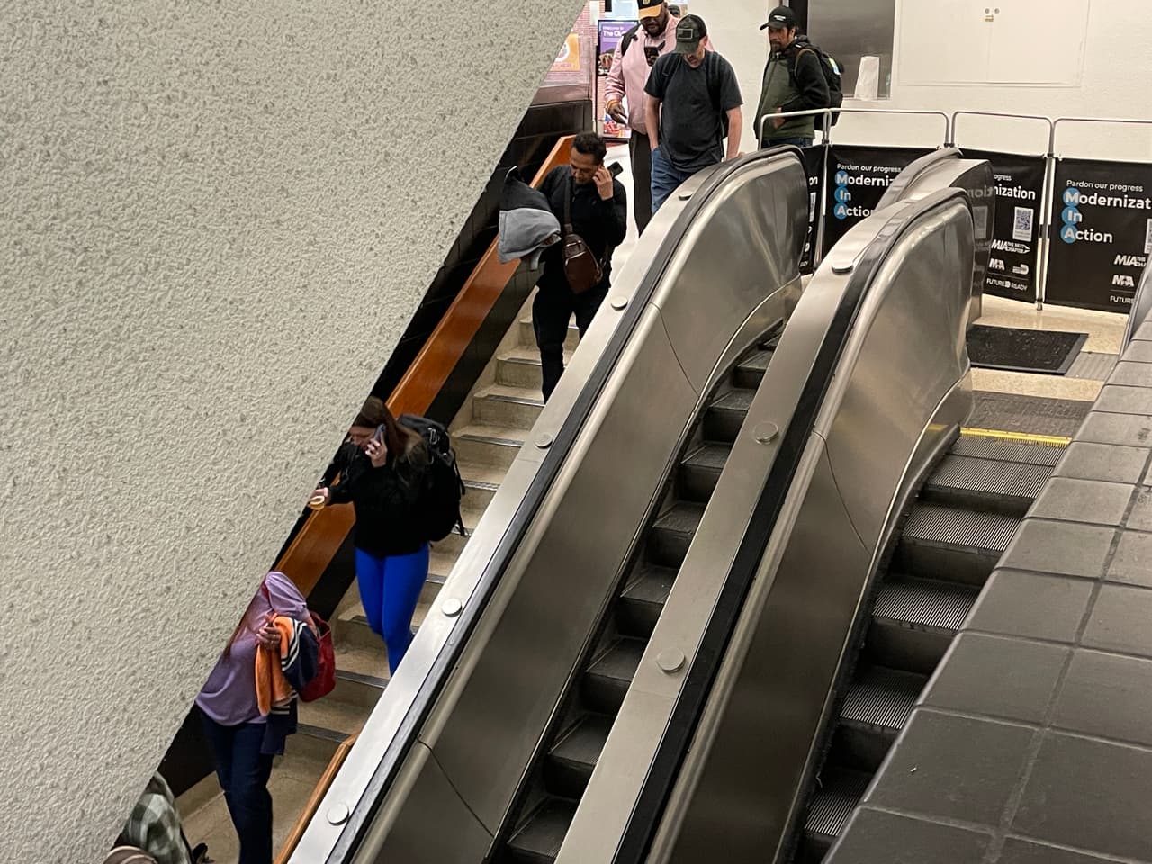 Turistas y pasajeros locales ven con resignación como las escaleras mecánicas no funcionan.