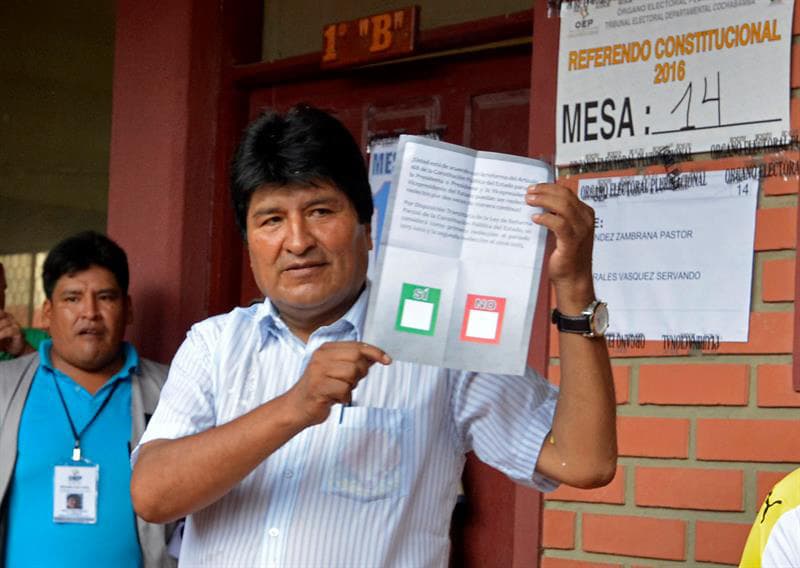 Evo Morales recibe su papeleta para votar en el referendo.