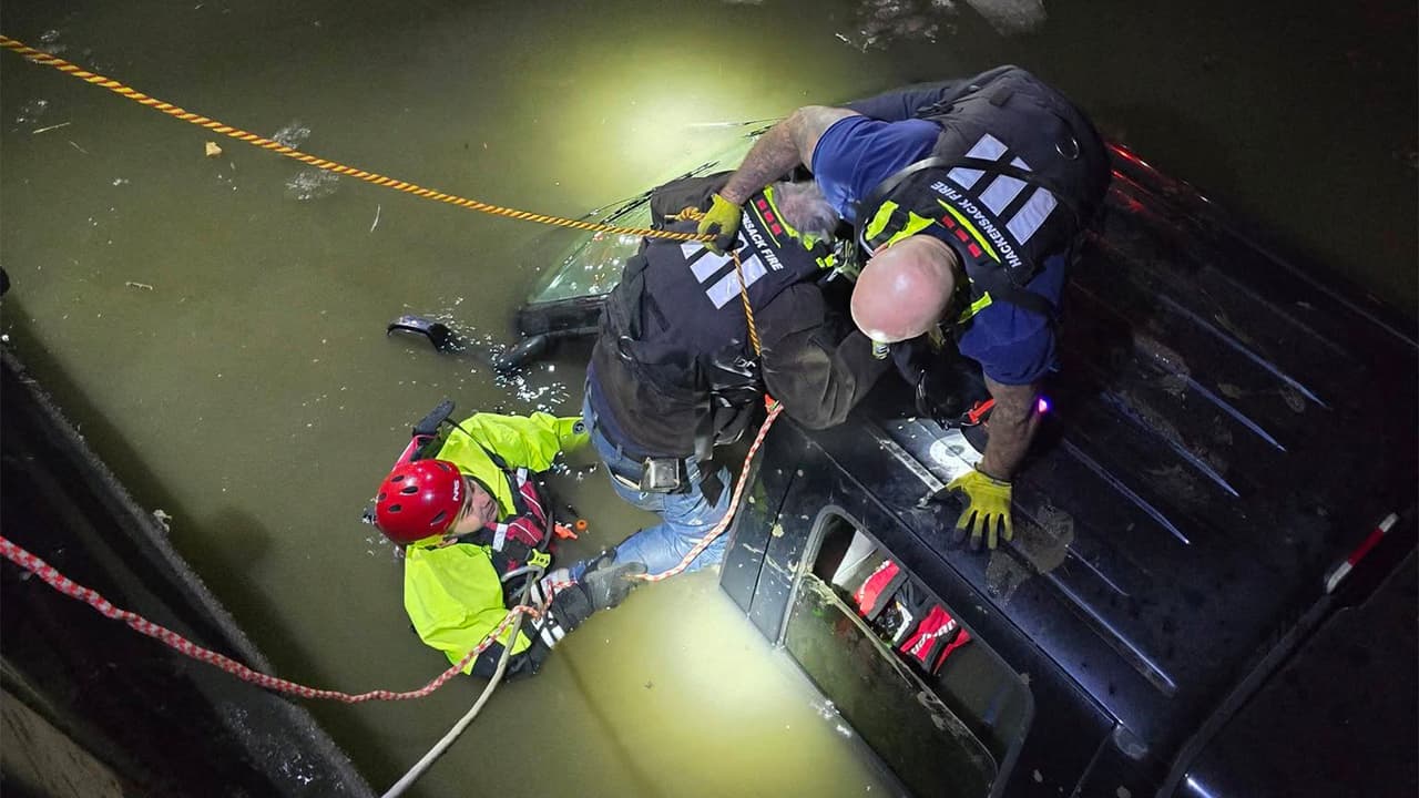 Dos bomberos descendieron al río con marea creciente para ayudar al conductor con la pierna atrapada.