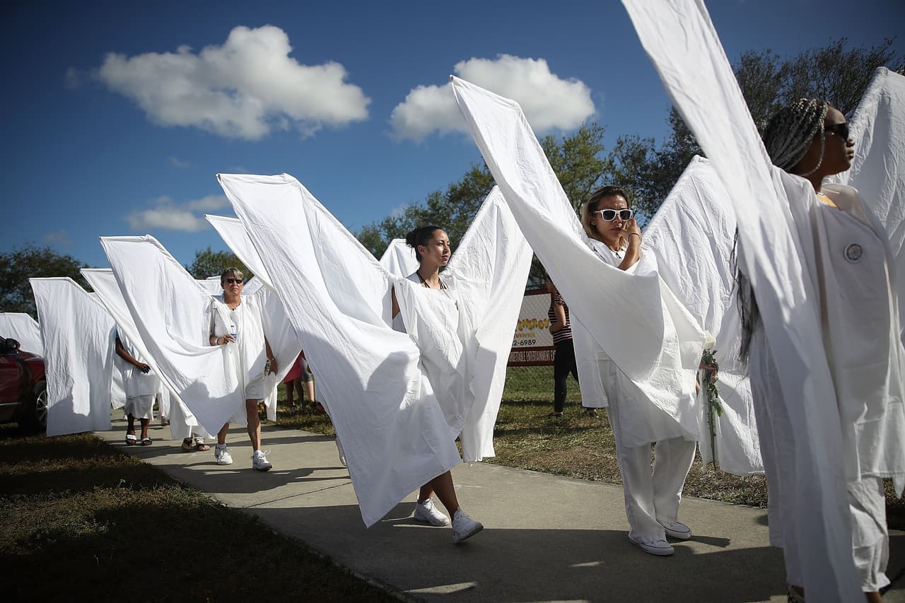 Personas vestidas de ángeles caminan en las instalaciones de la secundaria Marjory Stoneman Douglas, en Parkland, Florida, donde el pasado 14 de febrero ocurrió el tiroteo que dejó 17 víctimas mortales.