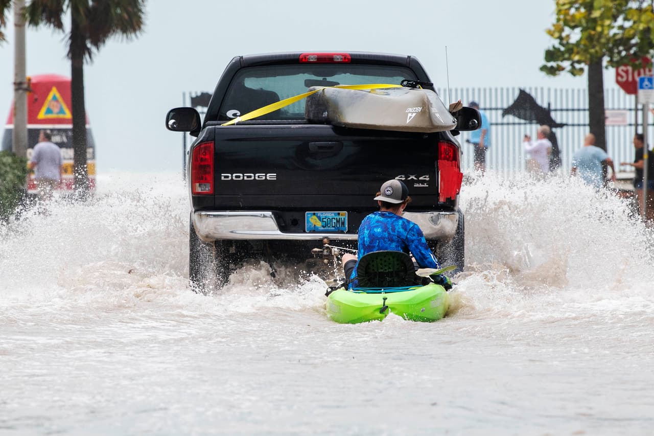 Un camión jala a un hombre en un kayak en un camino en Cayo West, Florida, la tarde de este miércoles. a marejada ciclónica podrían empujar de 3.6 a 5.5 metros (12 a 18 pies) de agua a lo largo de más de 400 kilómetros (250 millas) de costa, desde Bonita Beach hasta Englewood, de acuerdo con las advertencias de los meteorólogos.