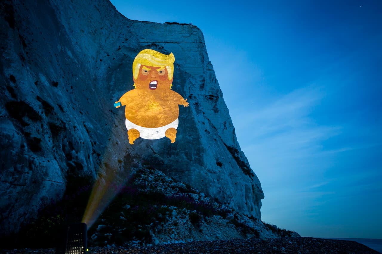El ‘bebé Trump’ inflable, que protagonizó las protestas de la anterior visita de Trump a Reino Unido, está programado para que vuele el martes sobre la capital británica. Mientras tanto los manifestantes proyectaron una imagen del ‘bebé Trump’ en los acantilados blancos de Dover, a unas 80 millas al este de Londres.