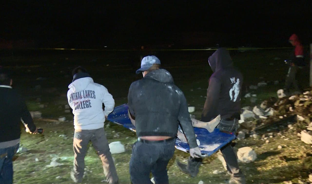 El cuerpo de una de las víctimas es llevado por varias personas tras la explosión.