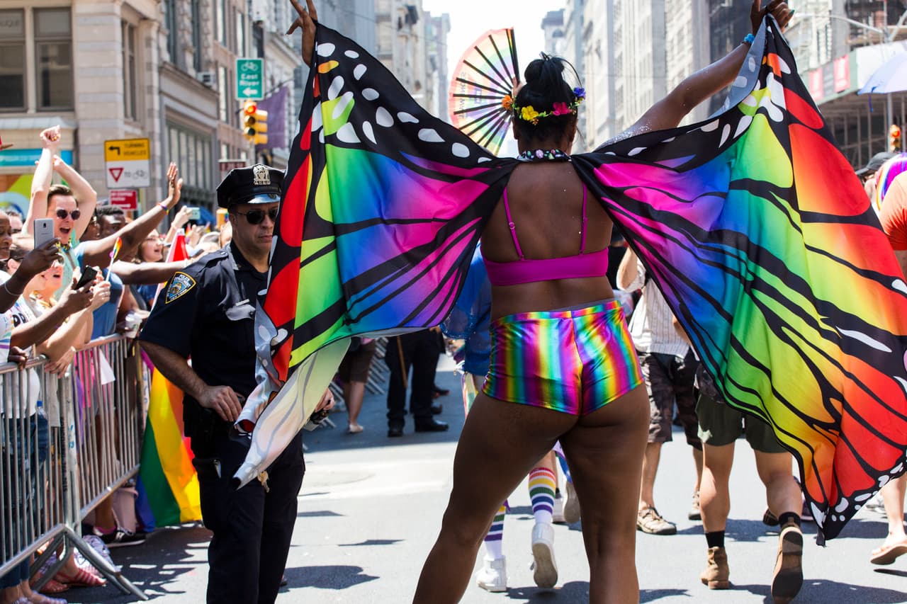 Un asistente al desfile usa alas de mariposa arco iris y pantalones cortos en el Desfile del Orgullo anual.