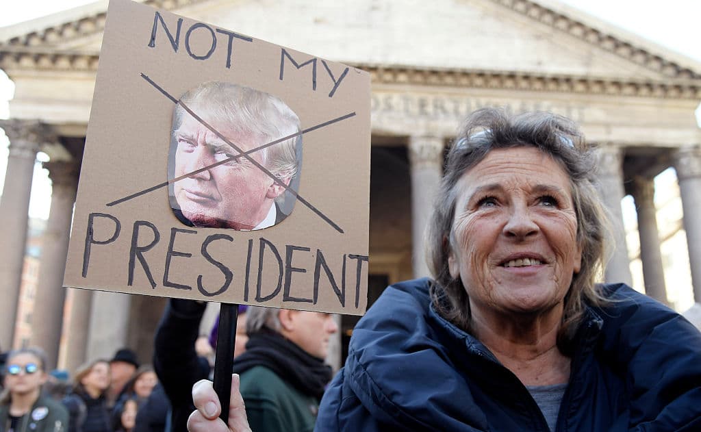 En Roma, Italia, esta mujer sostiene un cartel contra el presidente de Estados Unidos