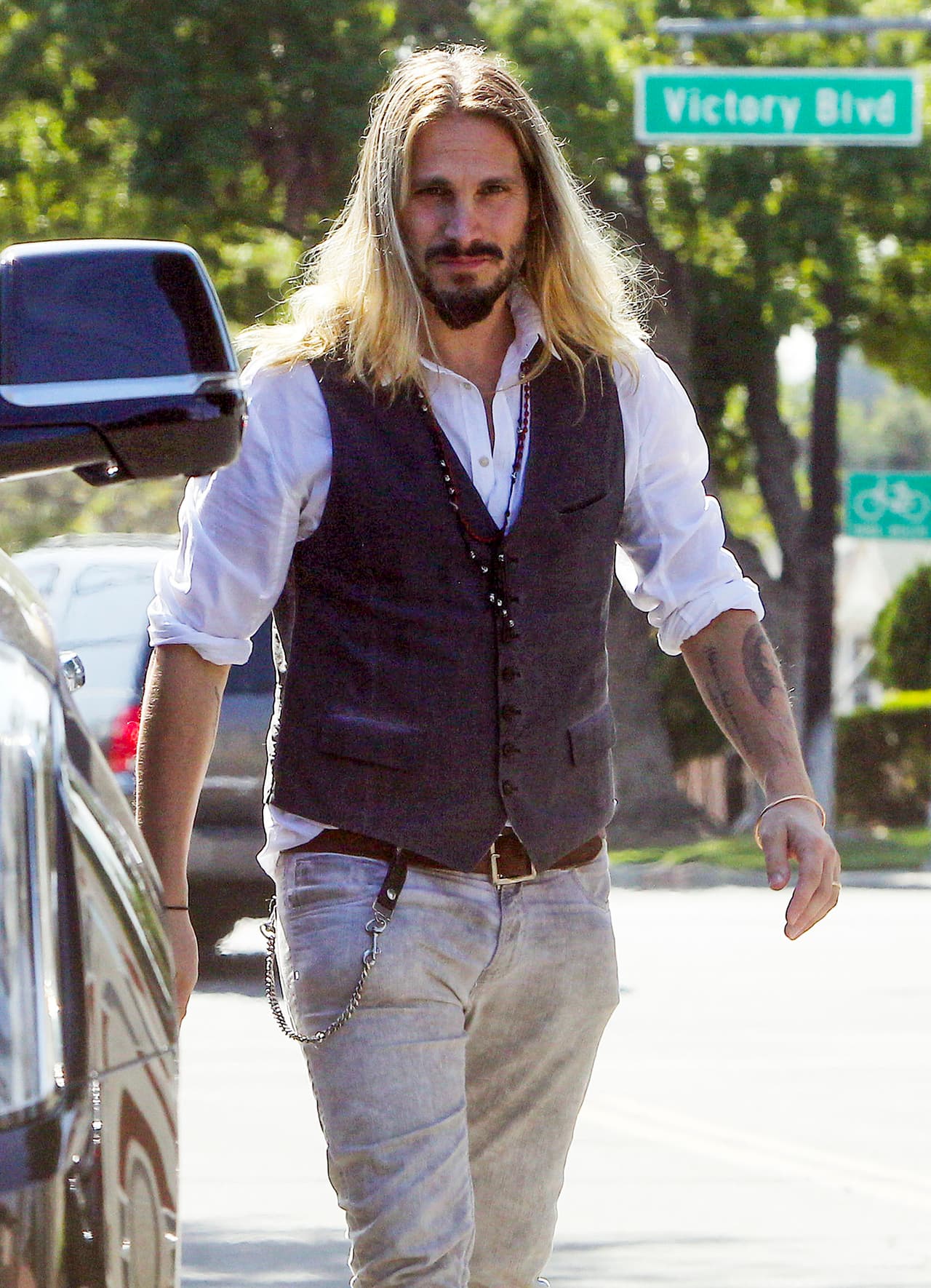 Marco con su cabello rubio suelto y un formal chaleco.