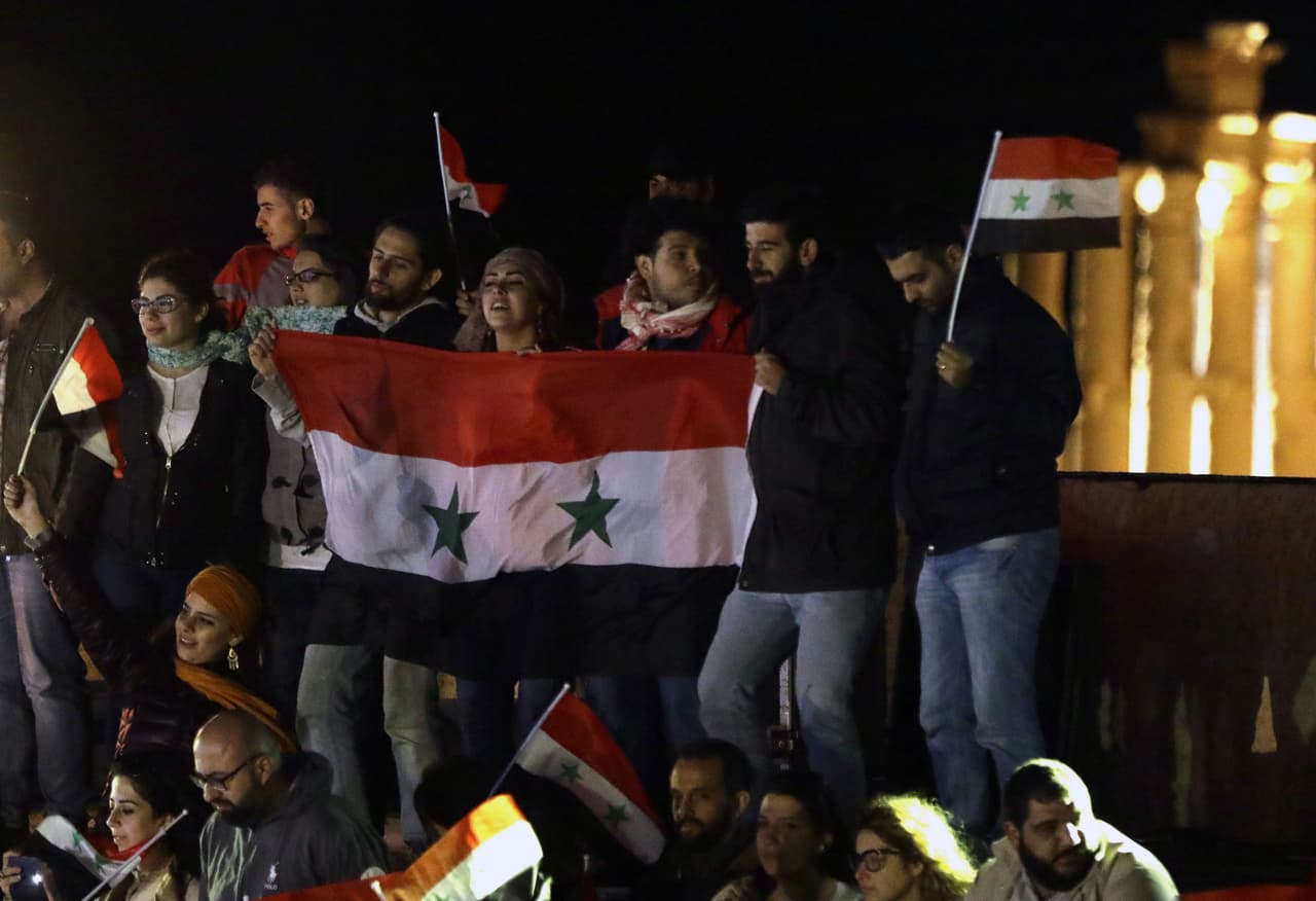 Los asistentes celebraron la recuperación de Palmira con banderas sirias.