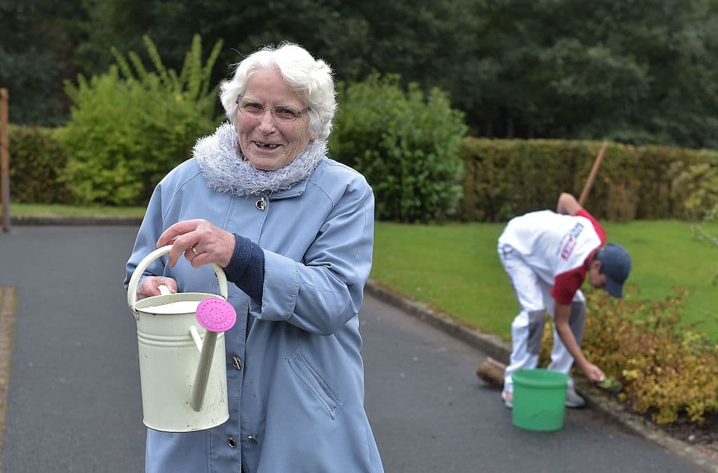 Una mujer con Alzheimer riega el jardín junto a un joven con dificultades psicológicas en una casa de retiro de Saint Quirin, en el este de Francia.