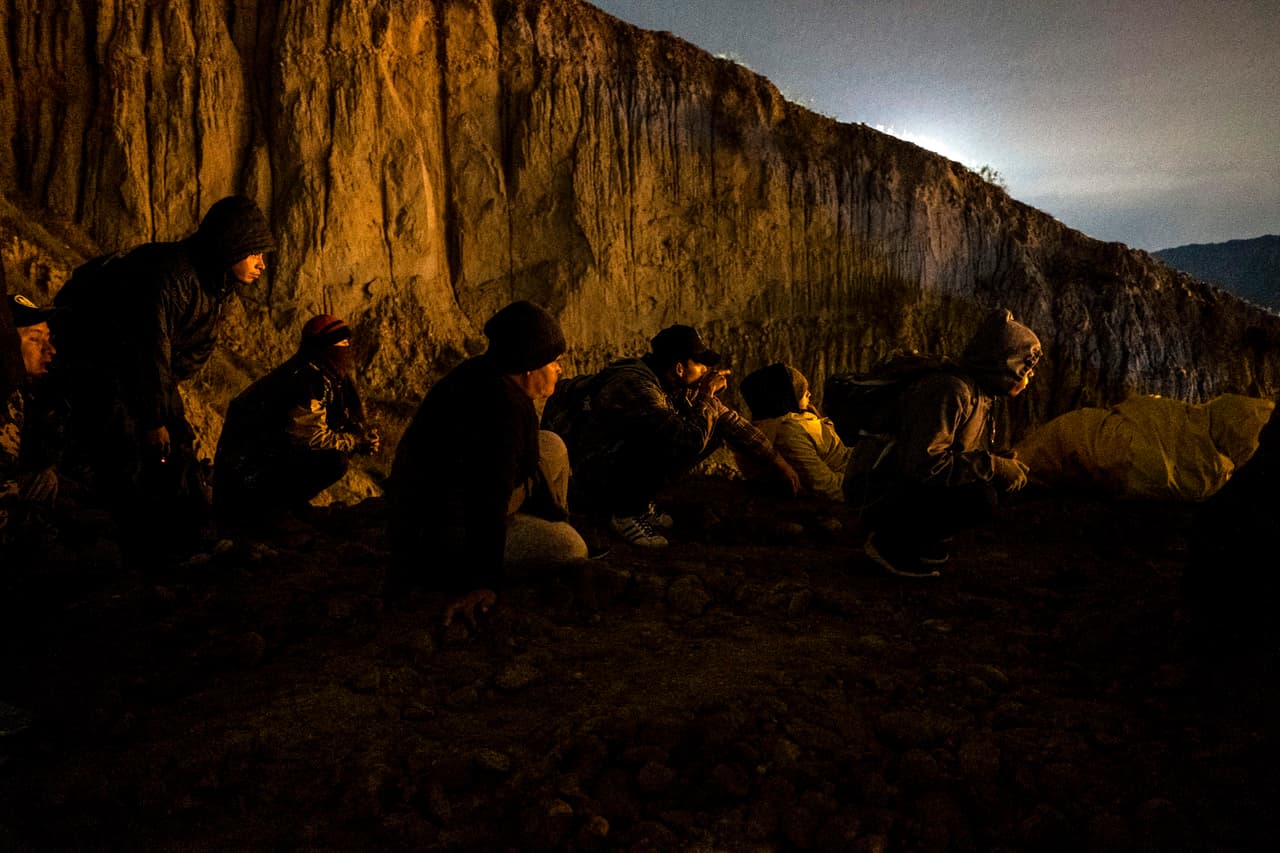 Un grupo de migrantes escondidos de la Patrulla Fronteriza cerca de la valla fronteriza entre México y EEUU, en Tijuana.
