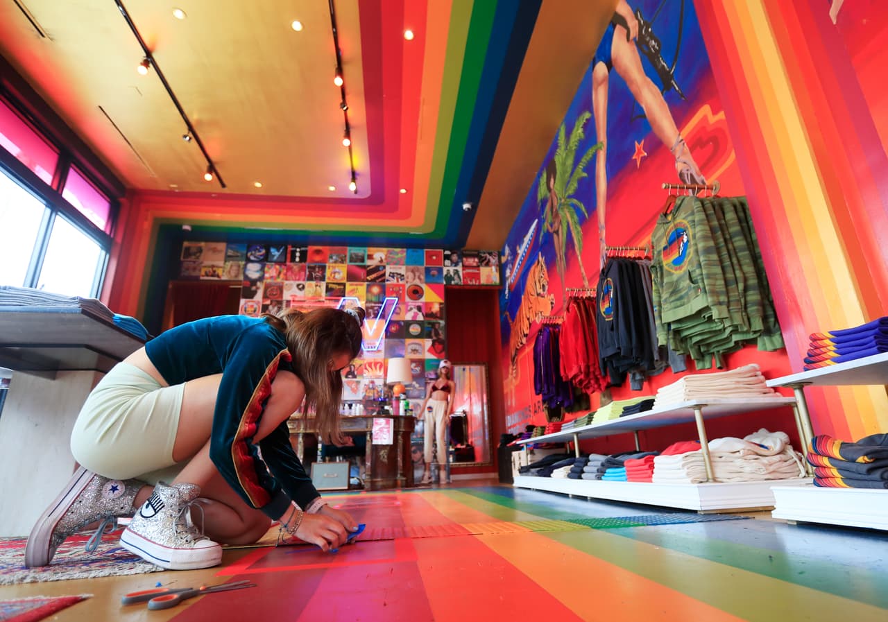 En esta foto una empleada de una tienda de ropa en Wynwood, marca los puntos con la distancia social que deben mantener los clientes. 
<br>