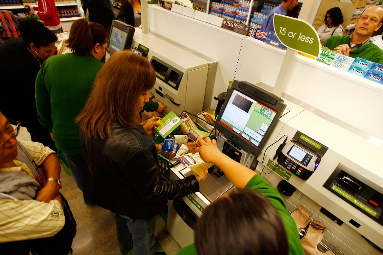 LOS ANGELES - NOVEMBER 08: Employees teach shoppers to use self-service checkout stations at a Fresh & Easy grocery as Tesco PLC, the UK's biggest retailer, officially enters the U.S. market, opening its first six stores in southern California on November 8, 2007 in Los Angeles, California. Tesco is importing its own system of grocery store operations, making heavy use of pre-packaged produce, in contrast to U.S.-based grocery chains, to reduce overhead and refrigeration costs. The Fresh & Easy markets, which are significantly smaller than typical U.S. supermarkets, will use its own truck fleet for single deliveries from a centralized distribution center. The chain will operate from a relatively small $10,000 per square foot, producing more than a projected $200,000 a week, twice that per square foot of typical U.S. food stores. (Photo by David McNew/Getty Images)