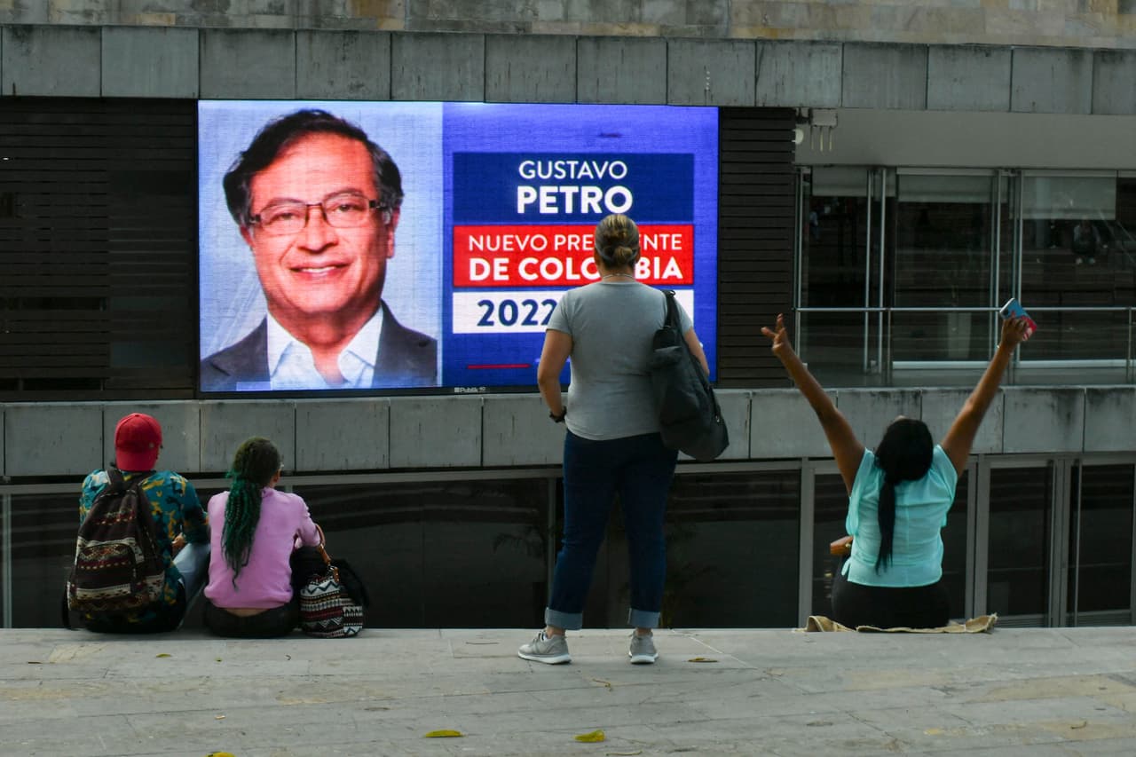 Una mujer, a la derecha, alza los brazos en señal de victoria frente a la pantalla que perfila a Gustavo Petro como ganador de la segunda vuelta de las elecciones colombianas.