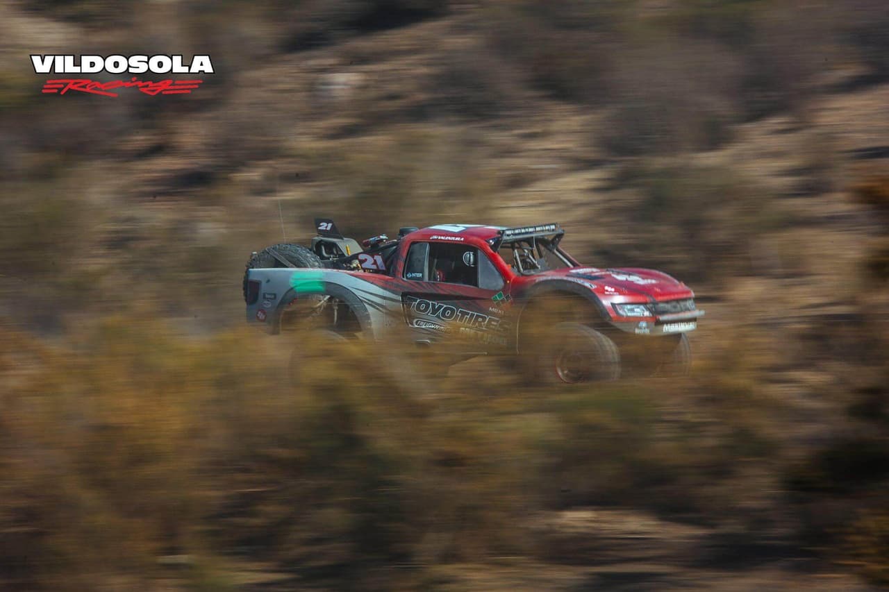 Vildósola Racing es una de las escuderías más grandes de Baja 1000,
<b> cuenta con el apoyo de grandes patrocinadores</b> y participa además en la Baja 500, la recién llevada a cabo carrera Vegas to Reno, la Mint 400, entre otras. El equipo ha ganado en dos ocasiones la Baja 1000 y este año se alió con Andy McMillin, otro piloto de familia off road, para competir juntos.
<br>El nivel de este equipo, completamente de grandes ligas, le permite tener vehículos fuertes para competir. Cuenta con una Ford SVT Raptor modificada en chasis por Vildosola Racing / Dave Clark, para ofrecer 830 caballos de fuerza y 750 libras pie, con un peso total de 5400 libras. Utiliza frenos Brembo de seis pistones, llantas BF Goodrich Baja T/A KR 39” x 13.5” R17 y transmisión tres velocidades: TH-400 Rancho Drivetrain Engineering. Su tecnología y equipamiento es superior a lo que la misma marca Ford ha puesto a prueba en esta competencia.
<br>