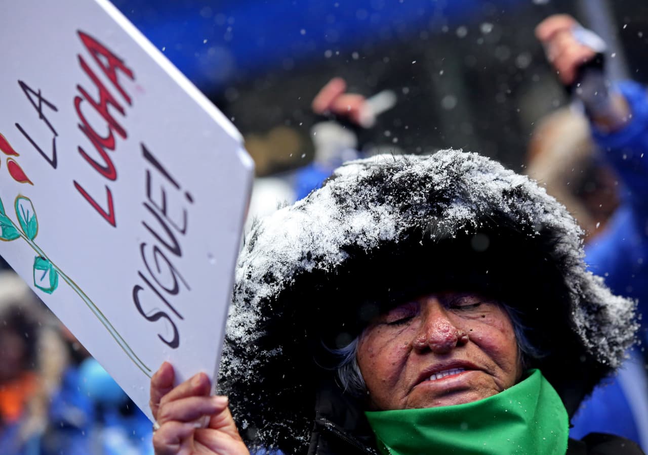 Una mujer entona "el Violador Eres Tú" mientras marcha en Nueva York con un letrero que dice "La lucha sigue".