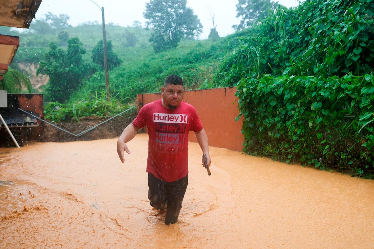 El huracán Fiona afectó la costa suroeste de Puerto Rico cuando desató deslizamientos de tierra, derribó la red eléctrica y arrancó el asfalto de las carreteras. En la foto, un hombre camina en una carretera inundada en Cayey.