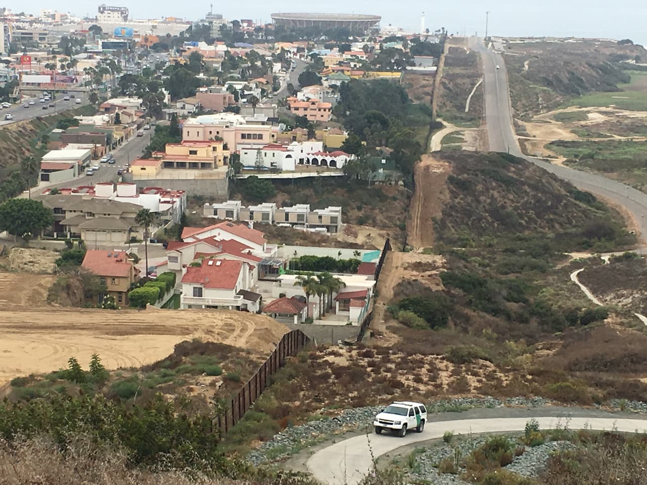 A la izquierda, Playas de Tijuana; a la derecha, un sector de San Diego por donde circula una camioneta de la Patrulla Fronteriza.