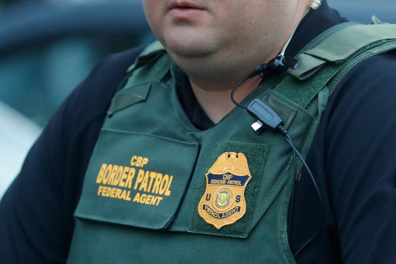 Un agente de la Oficina de Aduanas y Protección Fronteriza de Estados Unidos (CBP), también involucrada en la redada, vigila a varios de los trabajadores detenidos.