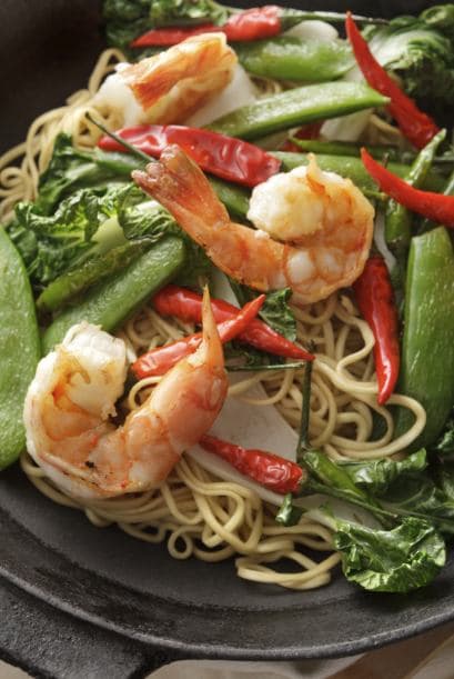 Cuando la pasta esté lista, cuélala y agrégala al wok junto con los camarones y 1 taza de jugo de naranja fresco.