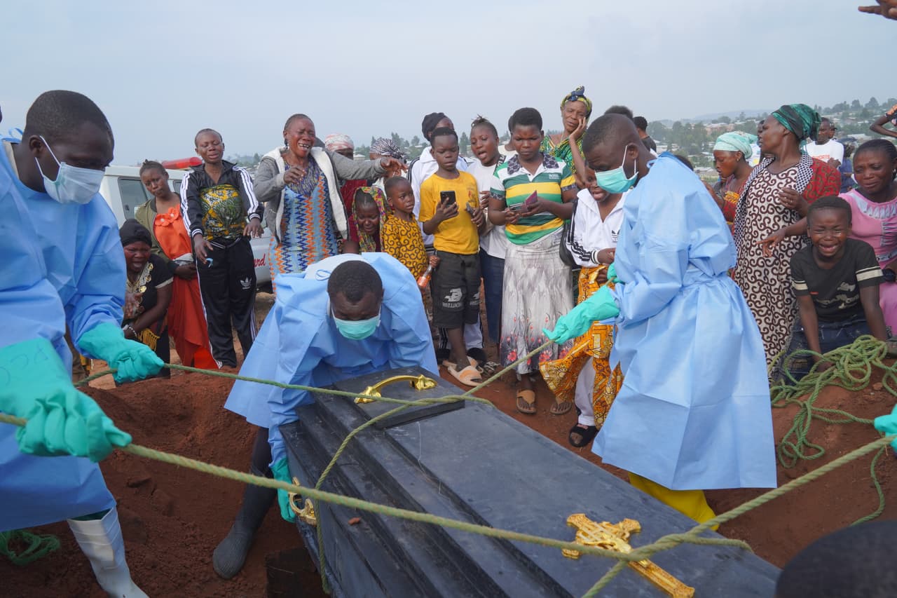Personas vestidas con equipo de protección descienden a una fosa el ataúd que contiene los restos de Jeannine Katusabe, fallecida a causa del ébola, durante un servicio funerario en Bunia, provincia de Ituri, en el este del Congo. (Foto AP/Dieudonne Dirole)