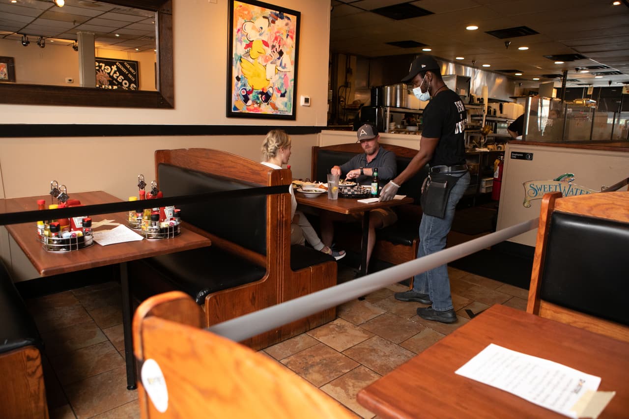 Ayite Medji (derecha) mesonero a la espera a Gene y Julia Schatlock para pedir comida en Roasters.